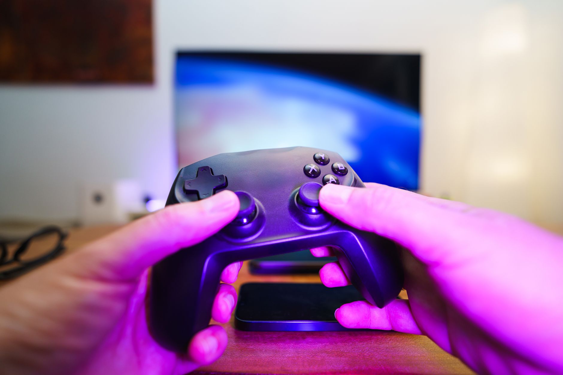 Close-up of hands holding a game controller in front of a TV screen. Perfect for entertainment setups. — Direct Baccarat Webs